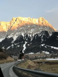 Road by snowcapped mountains against sky