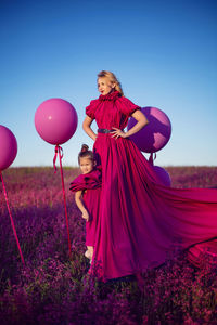 Family mother and daughter in pink dresses in a field with flowers and big balloons at sunset 