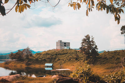 Trees and buildings by lake against sky