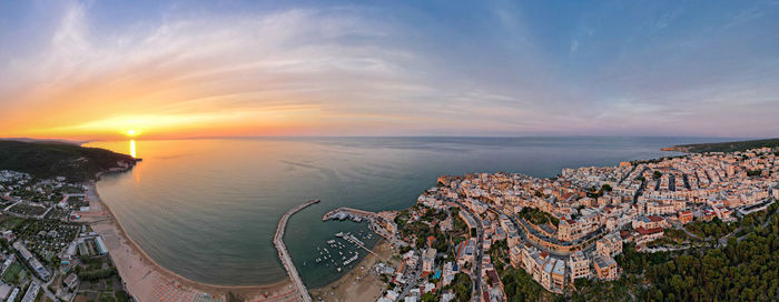High angle view of sea and buildings against sky during sunset