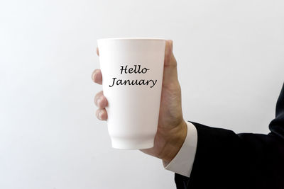 Midsection of man with coffee cup against white background