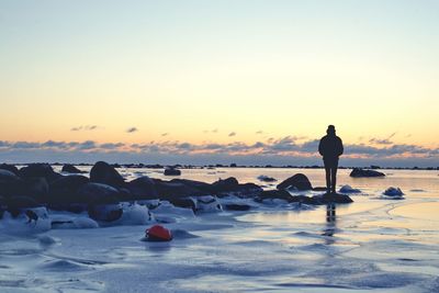 Silhouette man on beach against sky during sunset