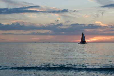 Sailboat sailing on sea against sky during sunset