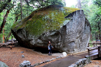 Woman standing by large rock