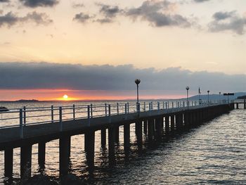 Pier over sea against sky during sunset