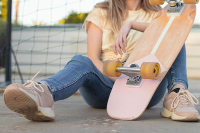 Unrecognizable portrait of a teenage girl sitting on the floor resting after a skate session