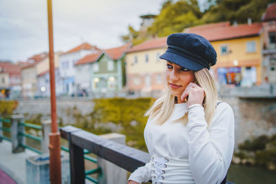 Young woman using mobile phone while standing against railing