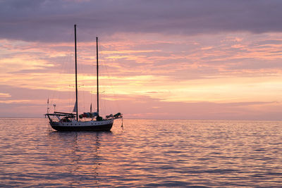 Boat sailing in sea at sunset