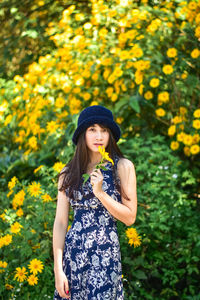 Young woman standing on yellow flowering plants