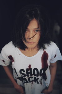 Close-up of girl looking away while standing against black background