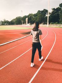 Full length rear view of woman walking on field