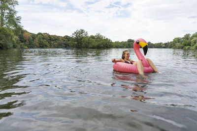 Young woman floating on a lake in a pink flamingo floating tire