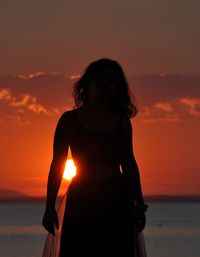 Woman standing at beach during sunset