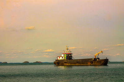 Fishing boat in sea against sky during sunset