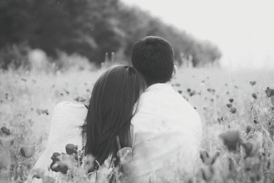 Rear view of couple relaxing in field