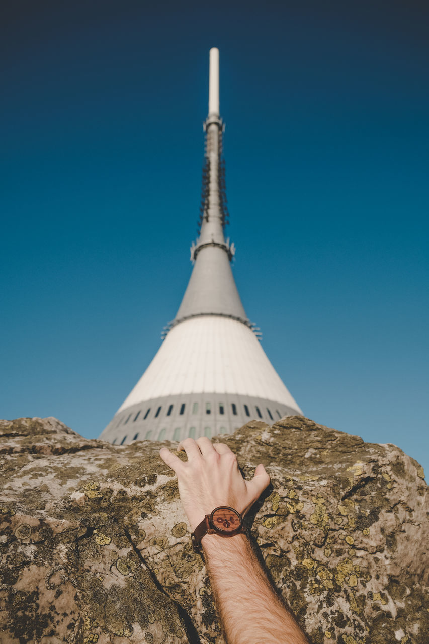 hand, human hand, personal perspective, sky, clear sky, real people, human body part, one person, day, nature, blue, architecture, outdoors, built structure, holding, unrecognizable person, body part, lifestyles, tall - high, finger, spire