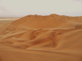 Sand dunes in desert against clear sky