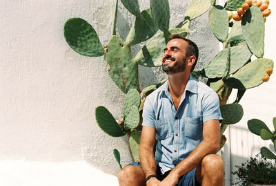 Young man sitting on cactus