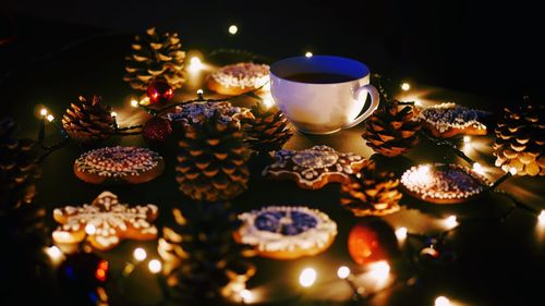 Close-up of cookies and tea with illuminated christmas lights on table