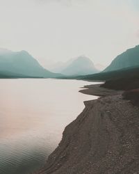 Scenic view of lake and mountains against sky at glacier national park during sunset