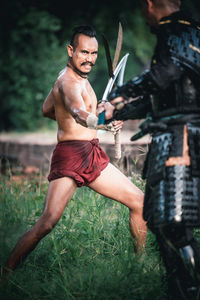 Full length of shirtless man standing on field