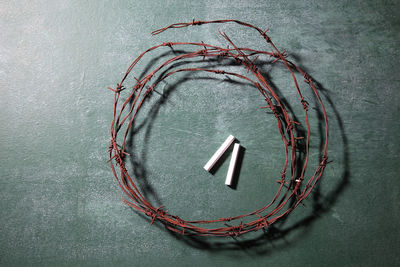 Directly above shot of rusty barbed wire with chalks on blackboard