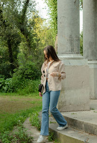 Full length of young woman standing against building
