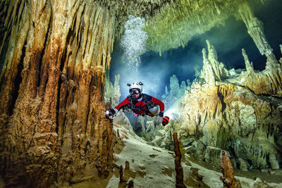 Person standing on rock formation in cave