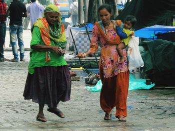 Full length of friends walking in city