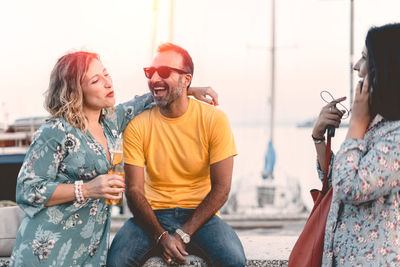 Cheerful couple with female friend at harbor