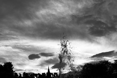 Low angle view of silhouette trees against storm clouds