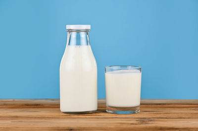 Glass of bottle on table against blue background