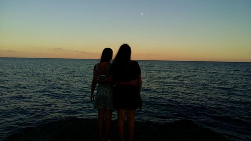 Woman standing on beach against clear sky during sunset