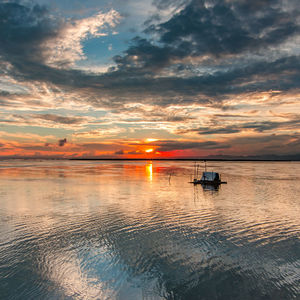 Scenic view of sea against dramatic sky during sunset