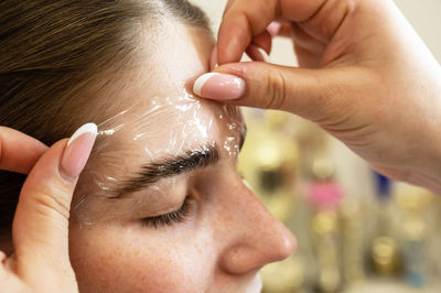 Cropped hands of beautician performing procedure on customers face