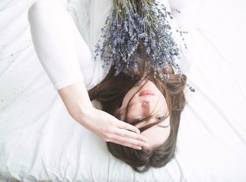 High angle view of woman with lavender flowers lying on bed at home