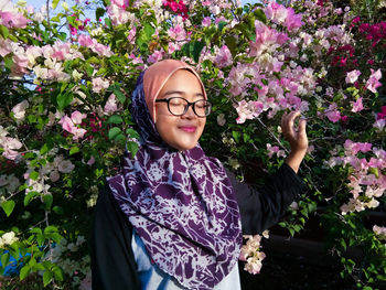 Woman wearing hijab while standing against flowers