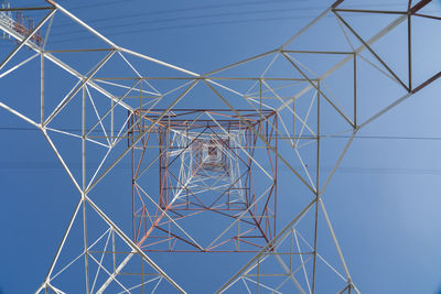 Low angle view of electricity pylon against blue sky