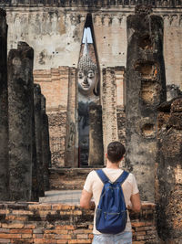 Rear view of man standing outside temple against building