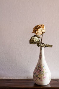 Close-up of vase on table against wall at home