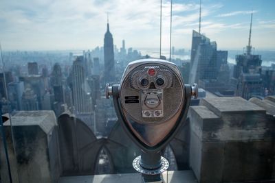 Close-up of coin-operated binoculars against cityscape