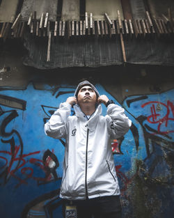 Full length of young man standing against wall