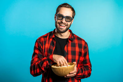 Portrait of a smiling young man against blue background