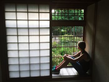 Full length of girl looking through window at home