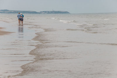 Rear view of people walking on beach