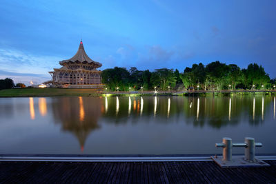 Sarawak state legislative assembly by river against blue sky