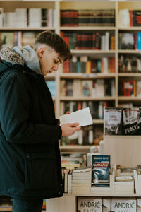 Side view of young man holding book