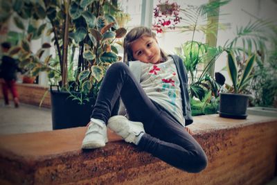 Girl looking away while sitting on potted plant