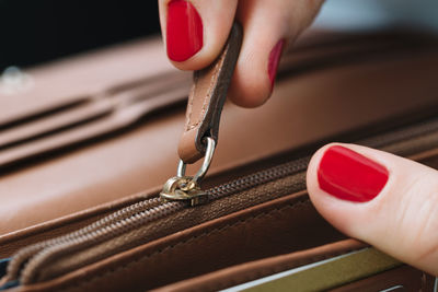 Close-up of cropped woman pulling clutch bag zipper