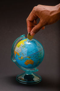 Cropped hand of man holding globe on table